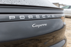 Close-up of the rear badge of a black Porsche Cayenne vehicle.