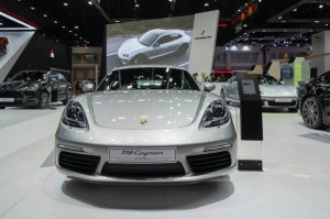 Silver Porsche 718 Cayman displayed at an indoor auto show.