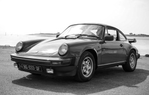 Classic Porsche 911 photographed in black and white near a waterfront.