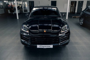 Black porsche cayenne displayed in a showroom.