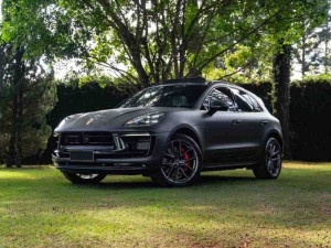 Matte grey Porsche Macan GTS parked on a green lawn.